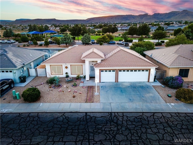 view of front of house featuring an attached garage, a tile roof, a mountain view, and stucco siding