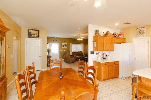 dining space with arched walkways, ceiling fan, light tile patterned floors, and visible vents