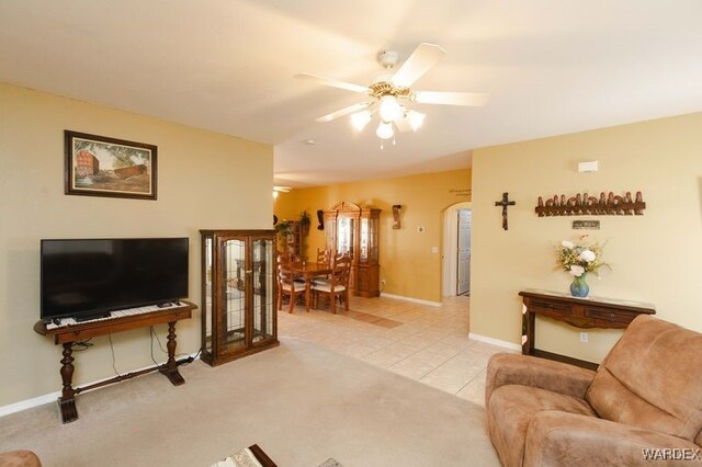 living room with light colored carpet, ceiling fan, baseboards, and light tile patterned floors