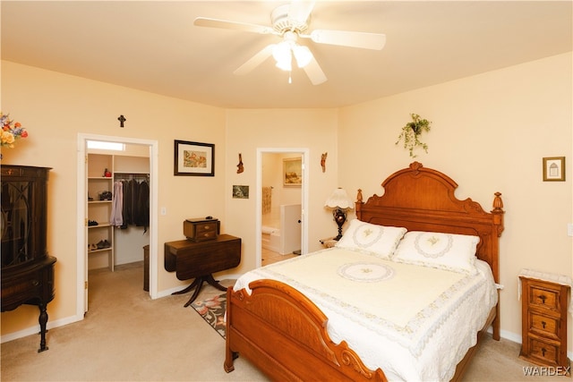 bedroom featuring a walk in closet, a closet, light carpet, connected bathroom, and ceiling fan