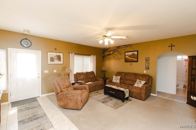 living room with a ceiling fan, arched walkways, baseboards, and light tile patterned floors