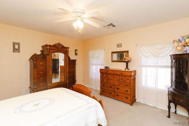 bedroom featuring baseboards, visible vents, a ceiling fan, and light colored carpet