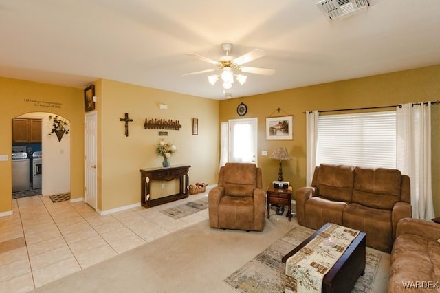 living room with arched walkways, ceiling fan, light tile patterned flooring, visible vents, and washing machine and clothes dryer