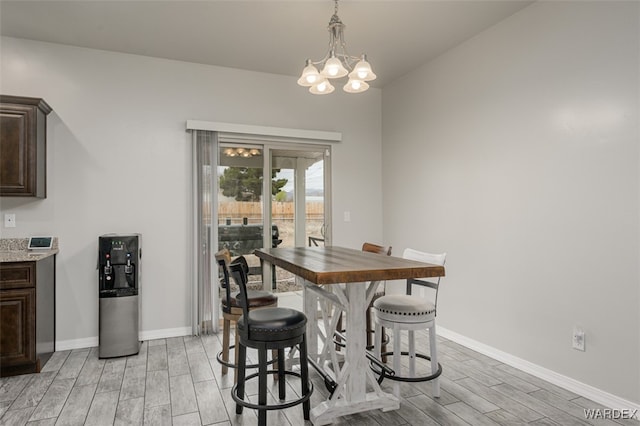 dining space featuring wood finish floors, baseboards, and a notable chandelier