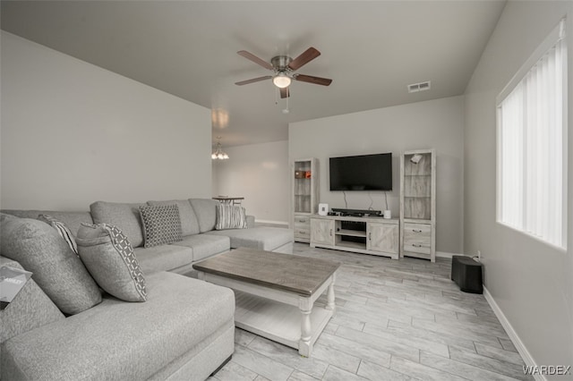 living room with visible vents, light wood-style flooring, baseboards, and ceiling fan