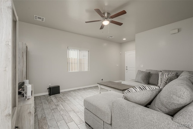 living room with baseboards, light wood-style floors, visible vents, and ceiling fan