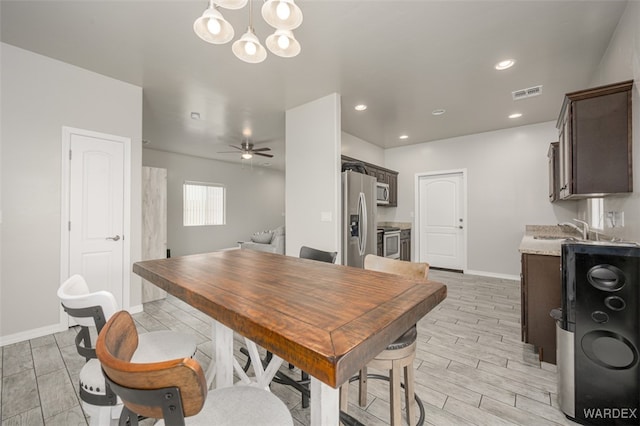 dining space with visible vents, baseboards, wood tiled floor, recessed lighting, and ceiling fan with notable chandelier