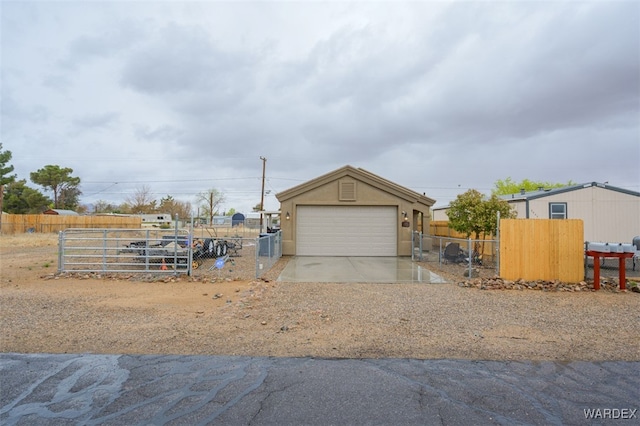 exterior space with concrete driveway, a gate, fence, and a garage