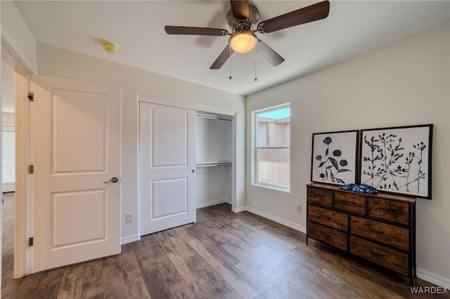 unfurnished bedroom featuring ceiling fan, a closet, baseboards, and wood finished floors