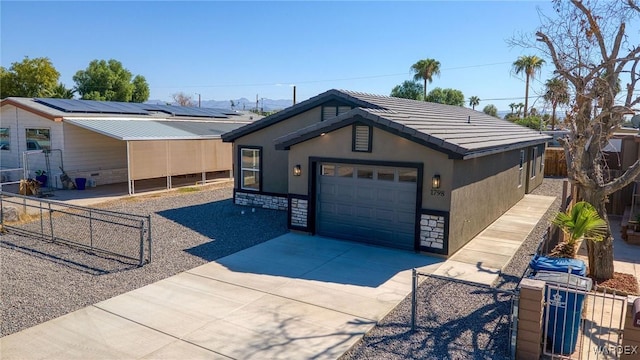 view of front facade with a tiled roof, fence private yard, stucco siding, a garage, and driveway