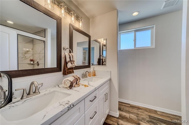 bathroom featuring a sink, visible vents, baseboards, and wood finished floors