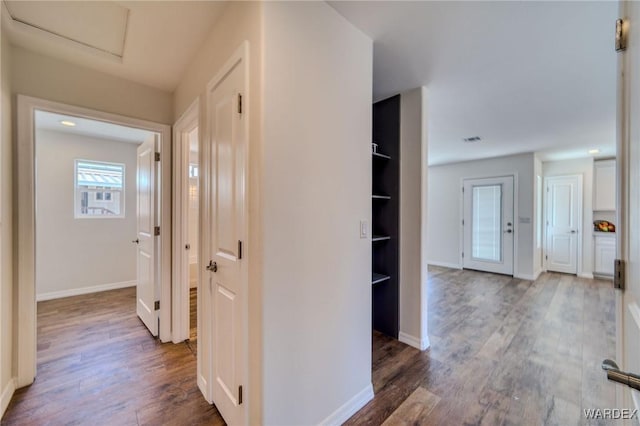 hall with visible vents, attic access, baseboards, and wood finished floors