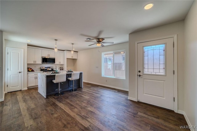 kitchen featuring dark wood finished floors, white cabinetry, stainless steel appliances, and baseboards