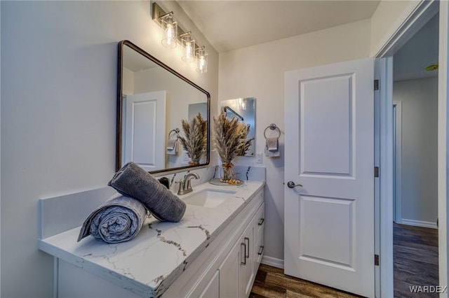 bathroom with baseboards, wood finished floors, and vanity