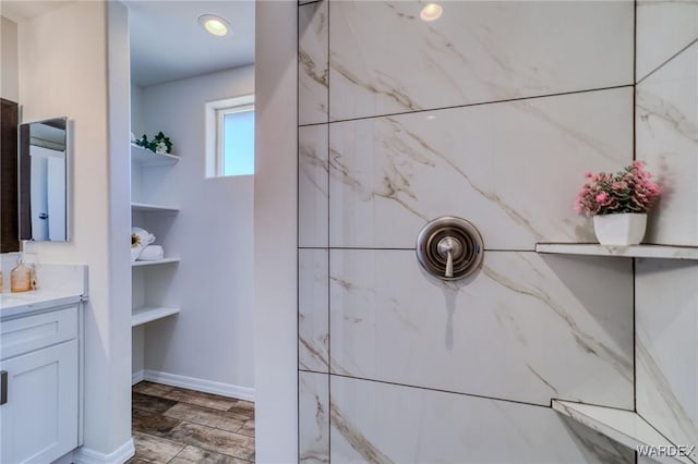 bathroom featuring a shower, baseboards, and vanity