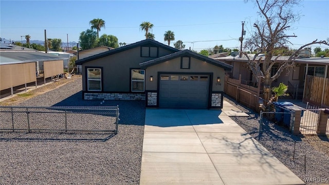 view of front of house with a fenced front yard, stucco siding, a garage, stone siding, and driveway