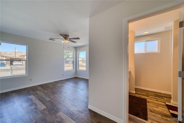 spare room with dark wood-type flooring, baseboards, visible vents, and a wealth of natural light