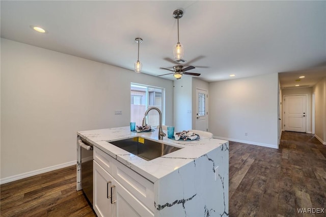 kitchen featuring a sink, dark wood-style floors, white cabinets, baseboards, and hanging light fixtures