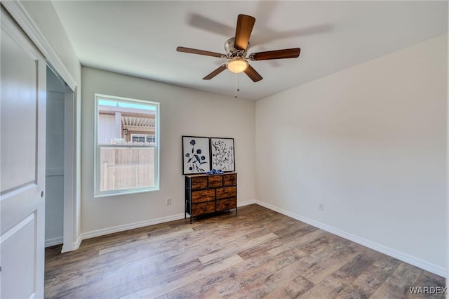 unfurnished bedroom featuring a closet, ceiling fan, baseboards, and wood finished floors