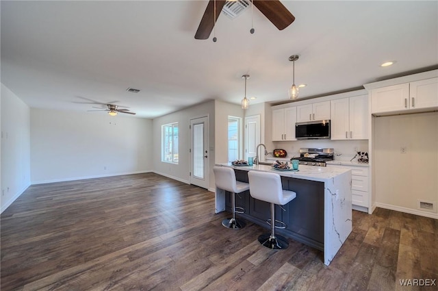 kitchen with stainless steel microwave, white cabinets, visible vents, and range