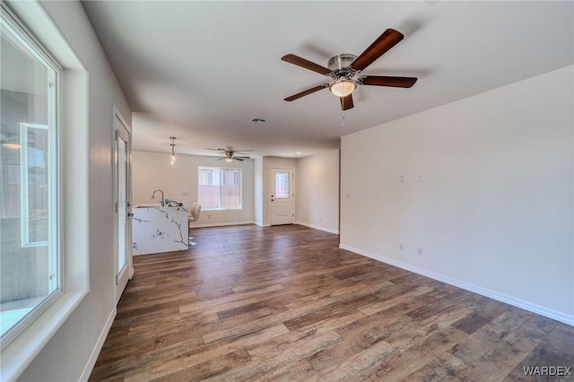 unfurnished room featuring a ceiling fan, wood finished floors, and baseboards