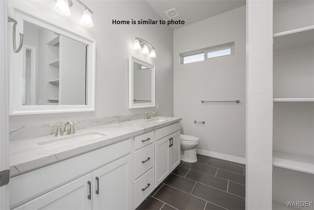 full bathroom featuring toilet, double vanity, a sink, and visible vents