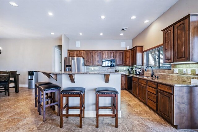 10726 S Shimmering Way, Mohave Valley, AZ 86440 - kitchen with black appliances, decorative backsplash, a kitchen breakfast bar, stone countertops, and recessed lighting