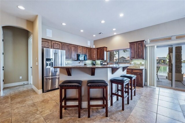 10726 S Shimmering Way, Mohave Valley, AZ 86440 - kitchen featuring high end fridge, black microwave, arched walkways, a breakfast bar, and a kitchen island