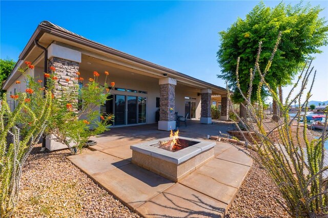 10726 S Shimmering Way, Mohave Valley, AZ 86440 - back of property featuring a fire pit, a patio area, stone siding, and stucco siding