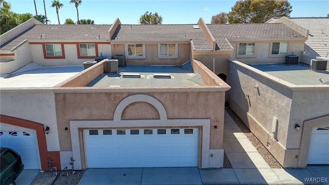 view of front facade featuring a garage, concrete driveway, central AC unit, and stucco siding