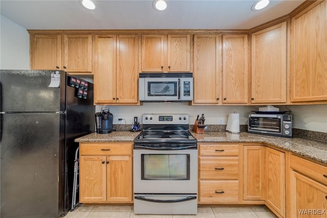 kitchen featuring stone counters, a toaster, stainless steel appliances, and light tile patterned flooring