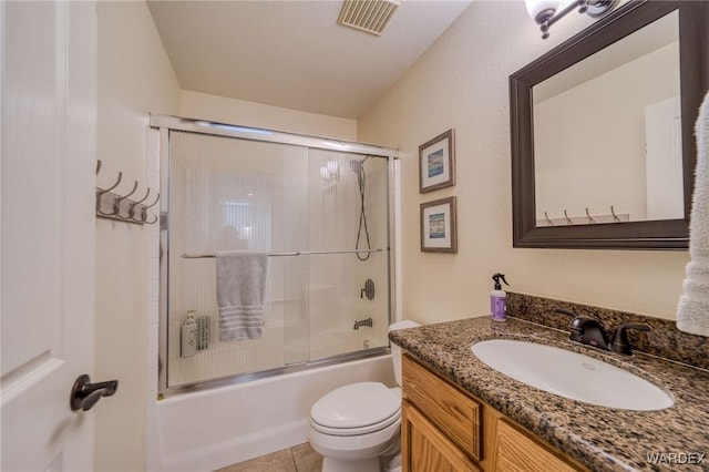 full bathroom with tile patterned flooring, toilet, vanity, visible vents, and combined bath / shower with glass door