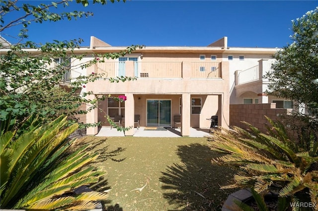 rear view of house with a patio area, fence, and stucco siding