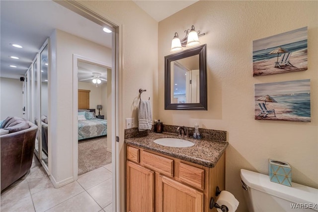 ensuite bathroom with connected bathroom, toilet, tile patterned floors, vanity, and recessed lighting