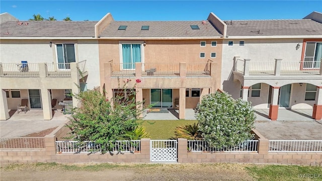 back of property featuring a patio, fence private yard, a balcony, and stucco siding