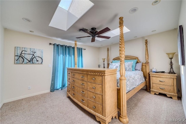 bedroom with a skylight, light carpet, ceiling fan, and baseboards