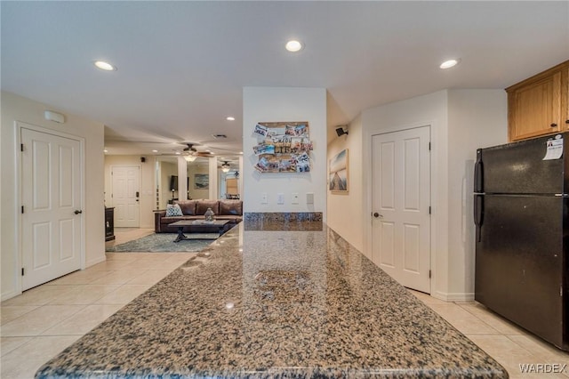 kitchen featuring dark stone countertops, freestanding refrigerator, and recessed lighting