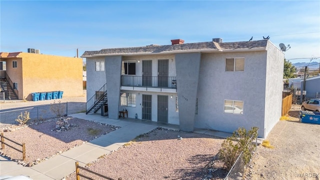 back of property featuring stairs, fence, and stucco siding