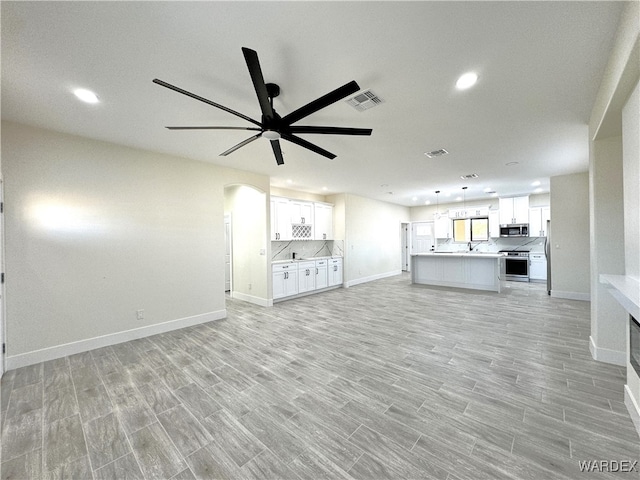 unfurnished living room featuring baseboards, visible vents, a ceiling fan, light wood-style floors, and recessed lighting