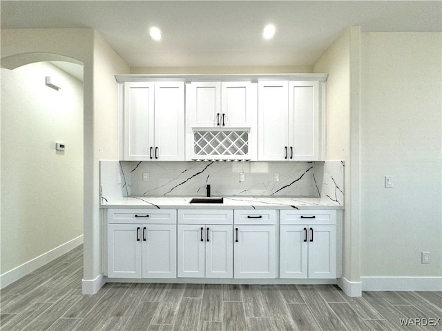 bar featuring tasteful backsplash, wood tiled floor, arched walkways, and baseboards