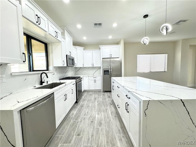 kitchen with stainless steel appliances, a sink, and white cabinets