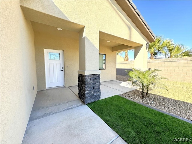 doorway to property with a patio, fence, and stucco siding