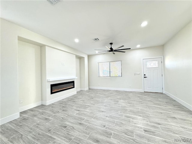 unfurnished living room featuring recessed lighting, visible vents, light wood-style floors, a glass covered fireplace, and ceiling fan