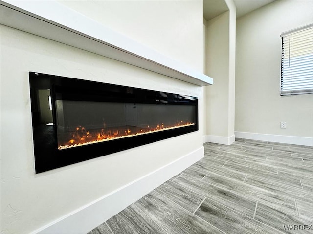 interior details featuring a glass covered fireplace, baseboards, and wood finished floors