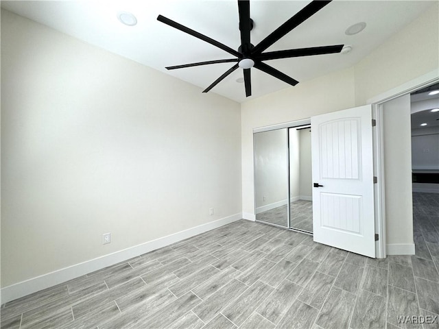 unfurnished bedroom featuring ceiling fan, wood finish floors, a closet, and baseboards