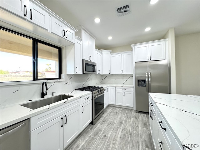 kitchen with appliances with stainless steel finishes, visible vents, a sink, and white cabinetry