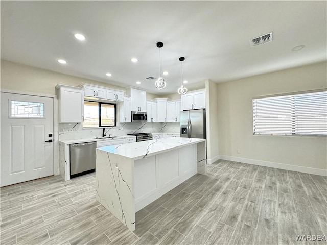 kitchen featuring stainless steel appliances, a sink, white cabinets, and a center island