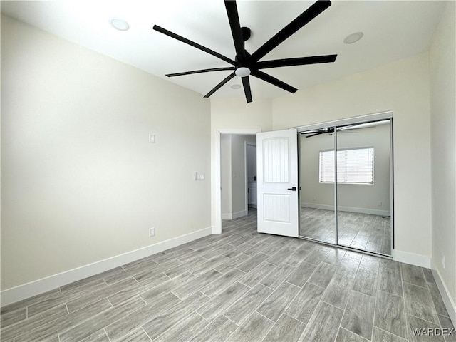 unfurnished bedroom featuring baseboards, ceiling fan, a closet, and wood tiled floor