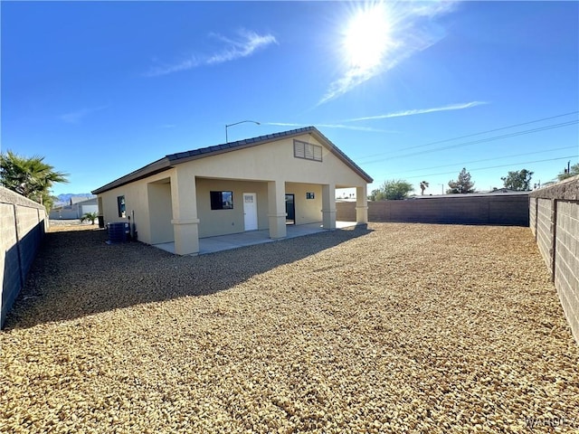 rear view of property with central air condition unit, a patio area, a fenced backyard, and stucco siding