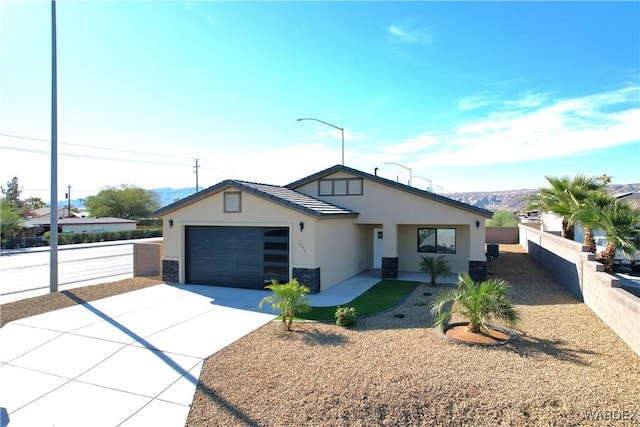 view of front of property featuring an attached garage, fence, concrete driveway, and stucco siding